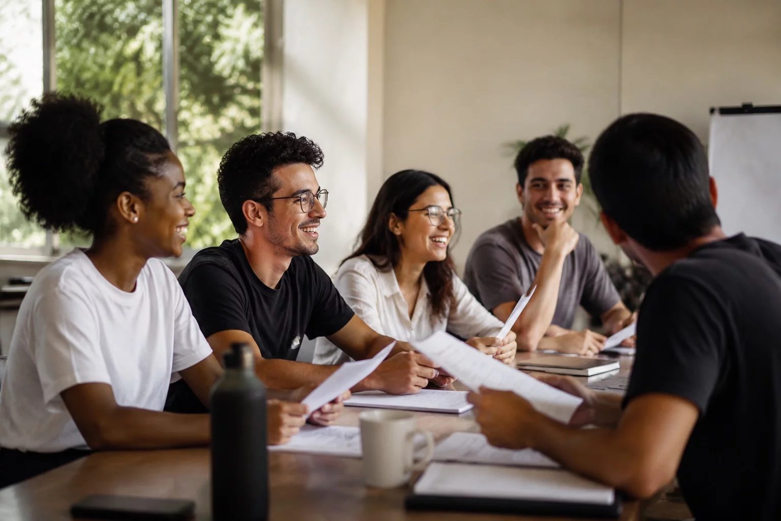 Grupo sorrindo após uma rodada de debate, com papéis nas mãos